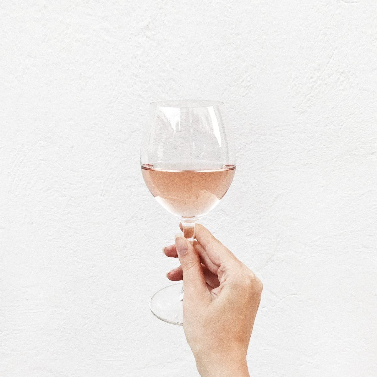 A hand holding a glass of rosé